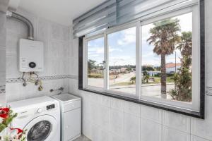 a laundry room with a washing machine and a window at FURADOURO - Vista dos Pinhais - apart 2 quartos a 100 metros da praia do Furadouro in Ovar