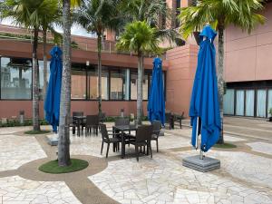 a patio with blue umbrellas and tables and palm trees at Glorious Service Suite At Times Square in Kuala Lumpur