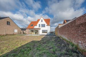 a white house with an orange roof and a brick wall at Villa Relax in Kortemark