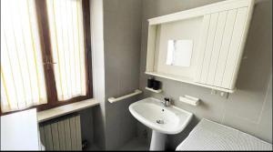 a white bathroom with a sink and a mirror at La Piazzetta, il centro di Biella in Biella +4 photos