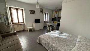 a bedroom with a bed and a couch and a kitchen at La Piazzetta, il centro di Biella in Biella