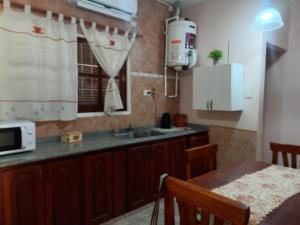 cocina con fregadero, microondas y mesa en Departamento Montevideana en Villa Mercedes