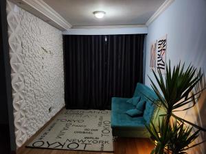 uma sala de estar com um sofá azul e uma cortina preta em Apê perto Alphaville em Osasco