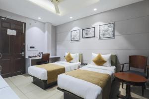 a hotel room with two beds and a desk at Cosy Grand, Near Chanakyapuri, Embassy Area in New Delhi