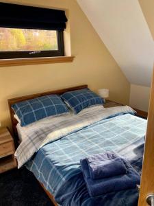 sypialnia z łóżkiem z niebieską pościelą i oknem w obiekcie Scottish Highland house near Fort William w mieście Corran