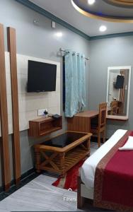 a bedroom with a tv and a bed and a desk at Hotel madhava in Naimishāranya