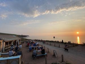 un grupo de personas sentadas en las mesas de la playa al atardecer en Avon Rock, en Kingsbridge