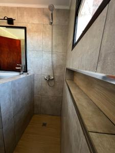 a bathroom with a shower with a sink and a mirror at Travesia Sur Hostel in El Bolsón