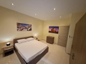 ein Schlafzimmer mit einem großen weißen Bett und zwei Gemälden an der Wand in der Unterkunft Tarxien - Lovely 3 bedroom unit in Tarxien