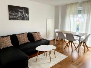 ein Wohnzimmer mit einem schwarzen Sofa und einem Tisch in der Unterkunft Holiday Apartment NAMASTAY in Küssaberg