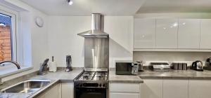 uma cozinha com armários brancos e um forno com placa de fogão em Bedford Street by Switchback Stays em Cardiff