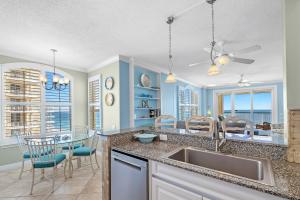 eine Küche mit Spüle und Tisch mit Stühlen in der Unterkunft Beach Colony Tower 14A in Pensacola