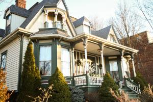 Una casa victoriana con adornos verdes y una torreta en MacFie House en Cape Girardeau