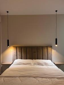 1 cama grande en un dormitorio con 2 luces encima. en Belix Hotel Apartments, Near the Beach en Durrës