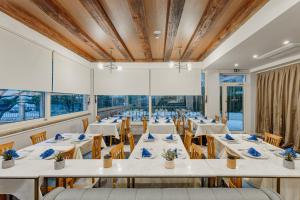 una sala da pranzo con tavoli e sedie bianchi di Hotel Splendido Bay a Tivat