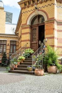 a building with stairs and potted plants in front of it at Gwuni B&B in Leipzig