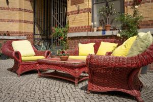 2 sillas de mimbre y una mesa con almohadas amarillas en Gwuni B&B, en Leipzig