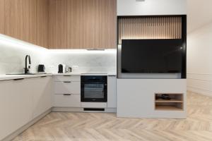 a kitchen with white cabinets and a flat screen tv at Lake Apart in Iława