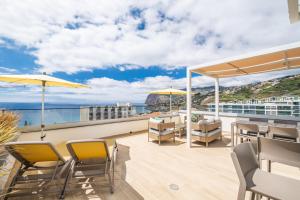 een balkon met tafels en stoelen en uitzicht op de oceaan bij SkyView Penthouse Apartment by MHM in Funchal
