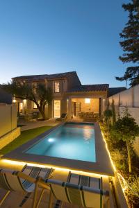 a swimming pool with chairs in front of a house at MAISON V AU COEUR DU VILLAGE Alpilles in Maussane-les-Alpilles