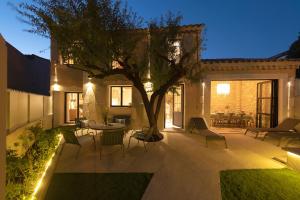 a patio with a tree and a table and chairs at MAISON V AU COEUR DU VILLAGE Alpilles in Maussane-les-Alpilles