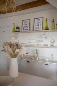 a white kitchen with a vase with flowers in it at MAISON V AU COEUR DU VILLAGE Alpilles in Maussane-les-Alpilles