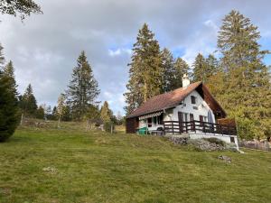 uma pequena casa no topo de uma colina relvada em Le Joly Chalet em Saint-Imier