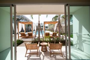 a patio with chairs and a table and a swing at Niranapa Boutique Resort in Kata Beach