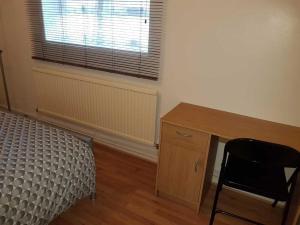 een slaapkamer met een bureau, een bed en een raam bij White City private room in Londen