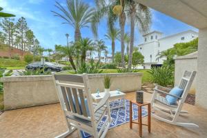 two chairs and a table on a patio with palm trees at La Costa Escape - Pool, BBQ, Gated Parking in Encinitas