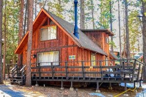 uma cabana de madeira na floresta com um alpendre em The Woodsy Whimsical Cabin em Big Bear Lake