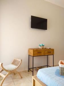 Cette chambre dispose d'une chaise et d'une télévision murale. dans l'établissement Stelia Apartment, à Ayiá