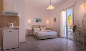 een slaapkamer met een bed en een keuken met een raam bij Aeolis Hotel in Adamas