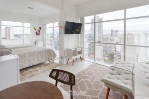 a white bedroom with a bed and a large window at Studio cond com piscina 180m hard rock café ESR1912 in Curitiba
