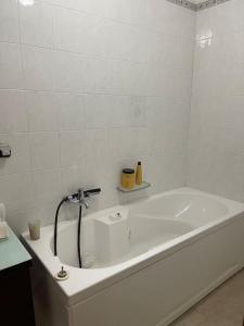 ein weißes Badezimmer mit einer Badewanne mit einem Wasserhahn in der Unterkunft N28 CoolNights in Torre Pelosa