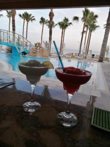 two cocktails sitting on a table next to a pool at Simos Magic Beach Hotel Apts in Ayia Napa