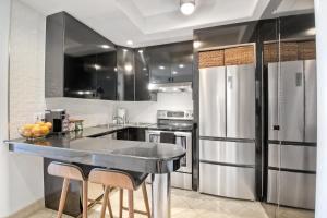 a kitchen with a stainless steel refrigerator and stools at Private Balcony Overlooking Pool - Gated Parking in Encinitas