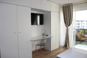 Habitación blanca con escritorio y TV en la pared. en L'oiseau du paradis - moderne et élégant en Cayenne