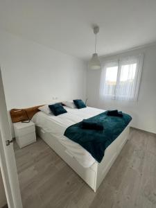 a white bedroom with a large bed with blue sheets at le Rocher in La Plaine-sur-Mer