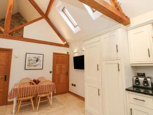 una cocina con armarios blancos y una mesa con sillas. en Sutton Newbold Cottage en Trimdon Grange