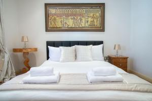 a bedroom with a white bed with a painting on the wall at Super Central beautiful 3 Bedroom in London