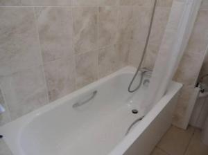 een badkamer met een wit bad en een douche bij White City private room in Londen