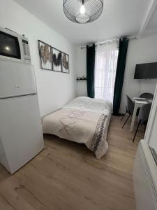 um pequeno quarto com uma cama e um frigorífico em Studio a deux pas de Paris em Levallois-Perret