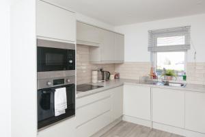 a white kitchen with white cabinets and a window at Entire Home, 2 Bedrooms - Private with FREE PARKING in Oxford in Oxford