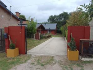 a driveway with a red gate and two potted plants at El Elyon Duplex in Santa Rosa de Calamuchita
