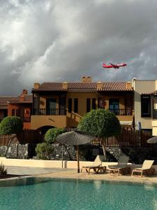 a plane flying over a house with a swimming pool at San Blas Golf del Sur Residence in San Miguel de Abona