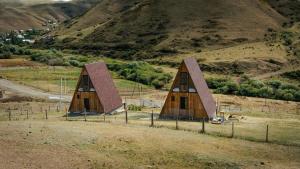 two small wooden barns in a field with a mountain at Focus Point Drakhtik - Green Cabin in Drakhtik