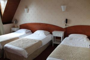 a hotel room with two beds and two tables at Hôtel Moderne in Gisors