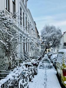 una calle cubierta de nieve con coches estacionados junto a los edificios en Zentrales und ruhiges Apartment im beliebtesten Bremer Viertel, en Bremen