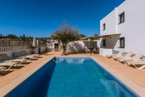 a villa with a swimming pool and lounge chairs at Villa Torres is a great villa only a 10 minute walk from the centre of Playa den Bossa in Ibiza Town